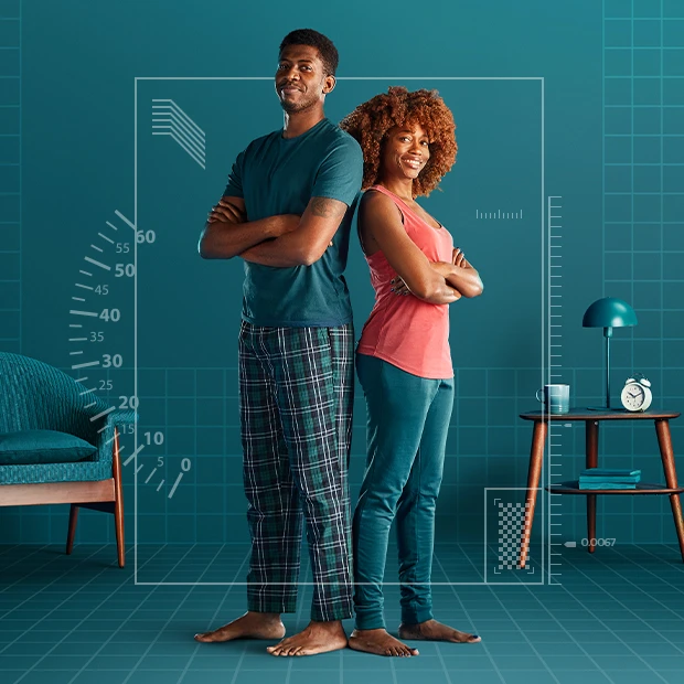 Couple stood back to back, in a bedroom surrounded by technical illustrations