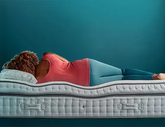 Woman laying on a mattress - side view showing mattress shape under body weight for spinal alignment