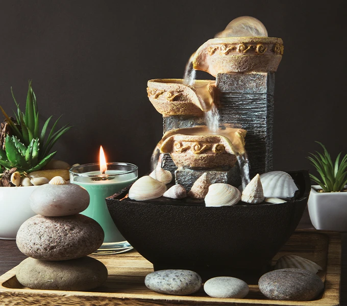 A small indoor water fountain next to a burning candle