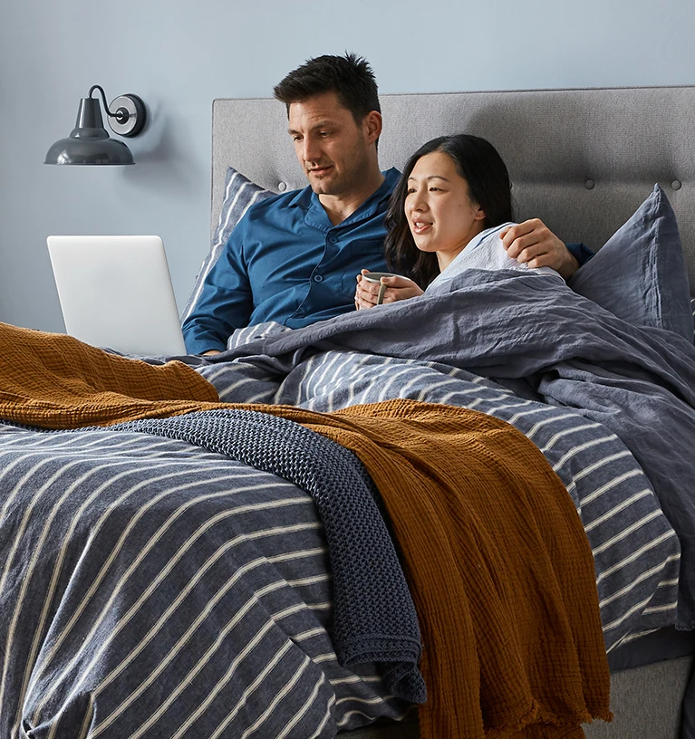 couple sat in bed, working on laptop