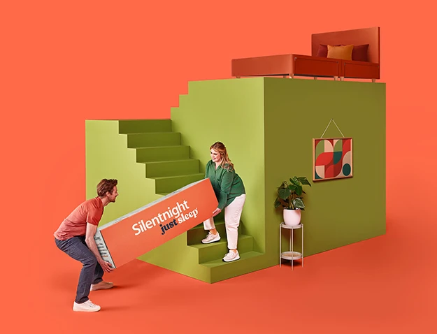 Man and woman carrying a just sleep rolled mattress up some stairs to a bedroom