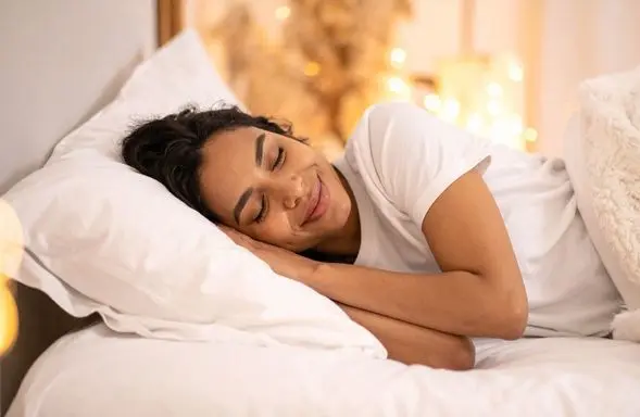 A woman sleeping in a bed on New Year's Day - good sleep habits for a happy new year 