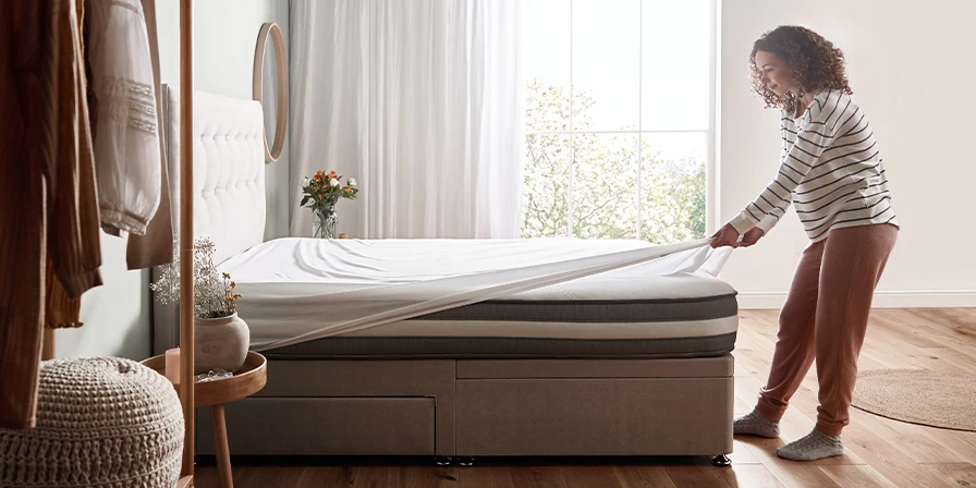 Woman putting fitted sheet onto mattress