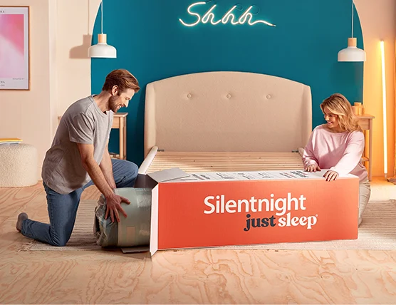 Two people unboxing a rolled mattress